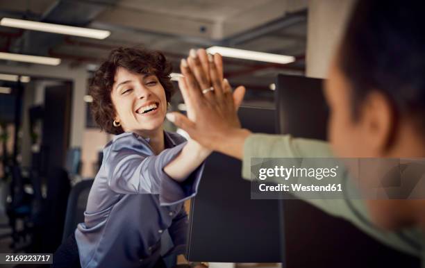 happy businesswomen giving high-five to each other at office - high five stockfoto's en -beelden
