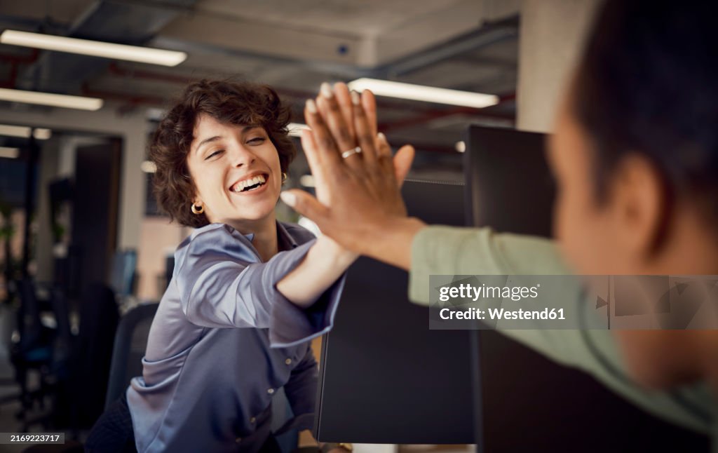 Happy businesswomen giving high-five to each other at office