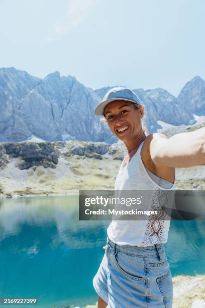 femme souriante prenant un selfie au bord d’un lac de montagne immaculé - état fédéré du tyrol photos et images de collection