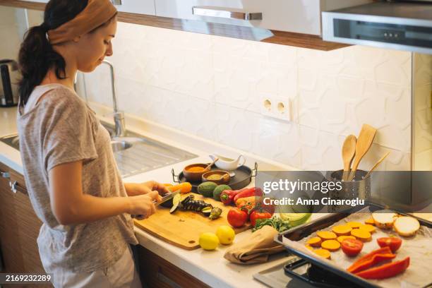 woman preparing fresh vegetables in a modern kitchen while cooking healthy meals - régime faible en glucides photos et images de collection