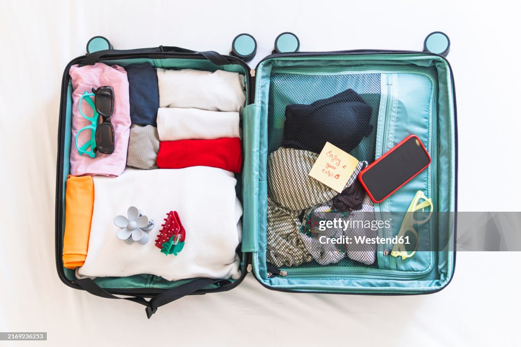 Open suitcase with clothes in hotel room