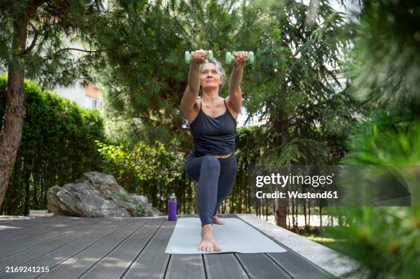 mature woman exercising with dumbbells at patio - hand weight stock pictures, royalty-free photos & images