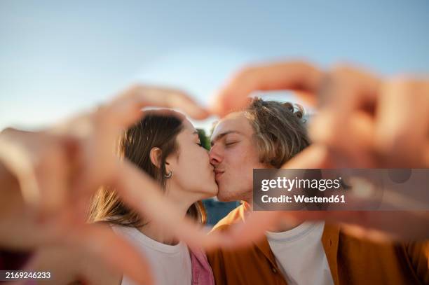 couple kissing and making heart symbol with hands - falling in love stock pictures, royalty-free photos & images