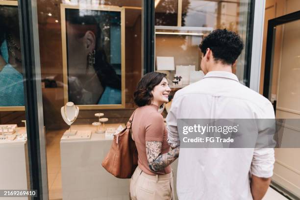 young couple looking at jewelry shop window - entering a men in a mall stock pictures, royalty-free photos & images