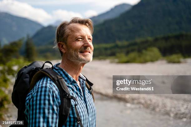 male hiker smiling and enjoying nature while hiking in the mountainous landscape of germany - bayern muster stock-fotos und bilder