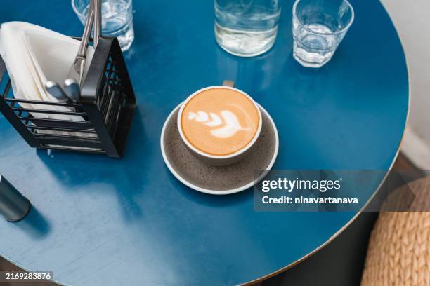 overhead view of a cappuccino and a glass of water on a table in a cafe - napkin holder stock pictures, royalty-free photos & images