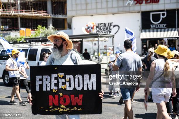 Man holding a placard reading 'Freedom Now' as citizens gather in the center of Tel Aviv, demonstrating and blocking roads to demand that the...