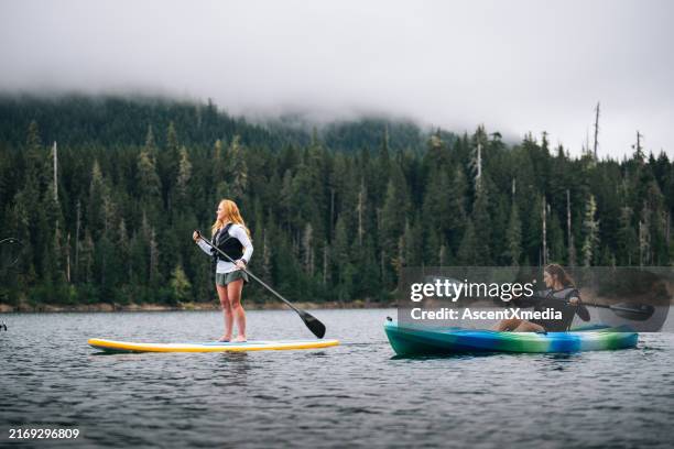 young women paddle sup board and kayak - de natuurlijke wereld stockfoto's en -beelden