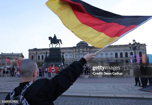 Skinhead supporter of the far-right Alternative for Germany political party waves a German flag while taunting leftist, anti-fascist protesters...
