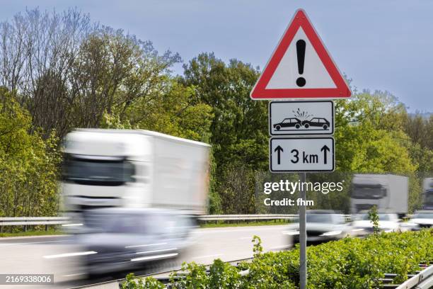trucks and cars on german autobahn with accident warning sign - señal de circulación fotografías e imágenes de stock