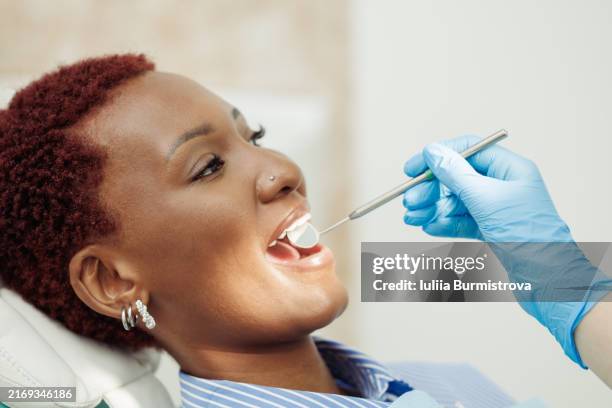 contented red-haired female patient sitting with open mouth during dental inspection - espejo dental fotografías e imágenes de stock