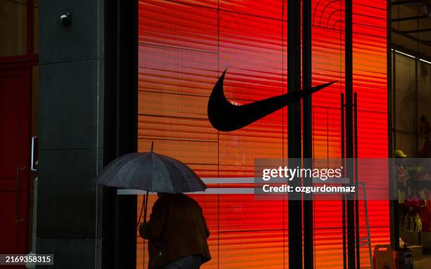 man walking in front of a nike retail store at night - editorial stock pictures, royalty-free photos & images