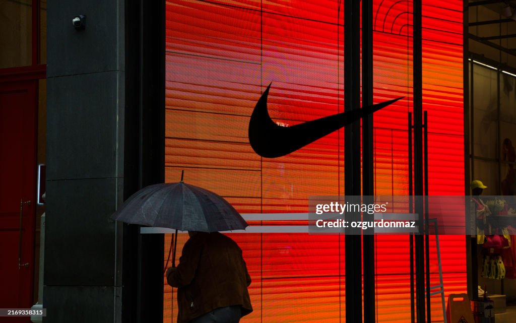 Man walking in front of a NIKE retail store at night