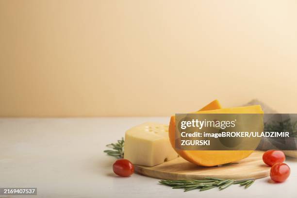 Various Types Of Cheese With Rosemary And Tomatoes On Wooden Board On A White And Orange Background And Linen Textile Side View Close Up Copy Space Selective Focus, Stockfoto