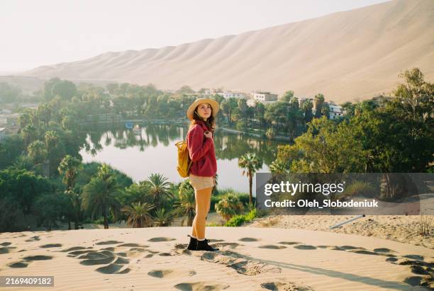 mujer de pie en la duna de arena mirando el oasis en huacachina, filmada en la película de la cámara - américa del sur fotografías e imágenes de stock