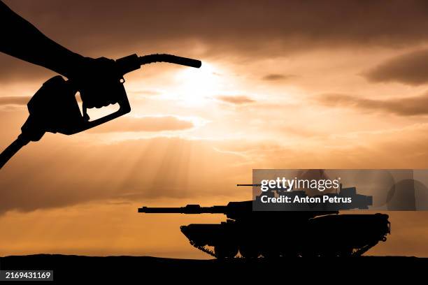 hand holding fuel nozzle over the armored tank - tanque de batalla principal fotografías e imágenes de stock