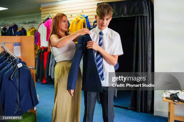a mother and teenage son shopping new clothes for school, trying on a school uniform - teens school uniform stock pictures, royalty-free photos & images
