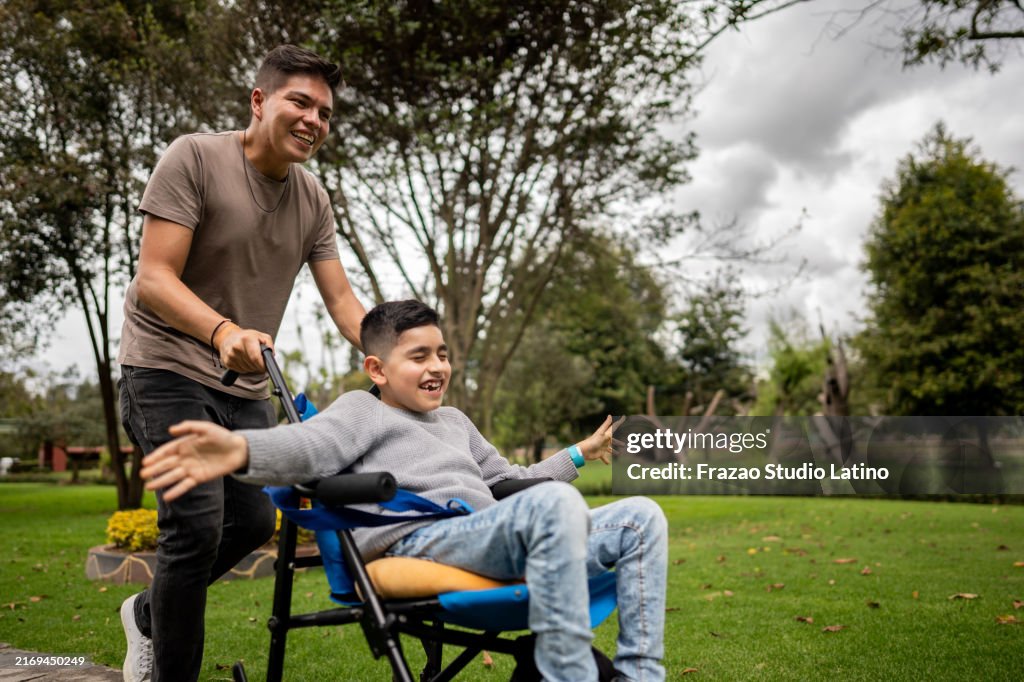Father and son with physical disability walking and playing on a public park