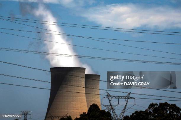 This photo taken on December 13, 2023 shows electricity lines passing near the emission funnels of the Bayswater coal-powered thermal power station...