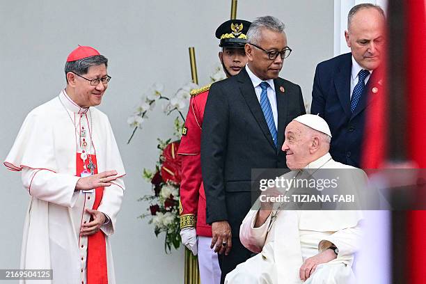 Pope Francis waves at Philippine Cardinal Luis Antonio Tagle during a ceremonial welcome at the Presidential Palace in Jakarta on September 4, 2024.