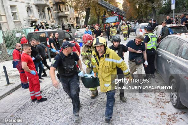 Injured local resident Jaroslav Bazylevych follows Ukrainian rescuers and policemen carrying the body of his daughter, who was killed along with her...