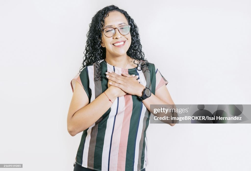 Positive smiling girl with hands on chest. Grateful people with hands on chest. Grateful young woman smiling with hands on chest isolated