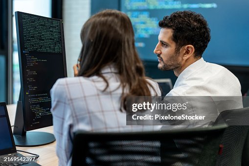 Two software developers checking programming code on computer screen. Two software developers checking programming code on computer screen.