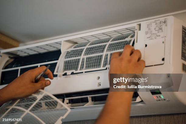 unrecognizable man returning new, cleaned filters back to air conditioner hanging on wall after purifying. - respiratory protection construction stock pictures, royalty-free photos & images