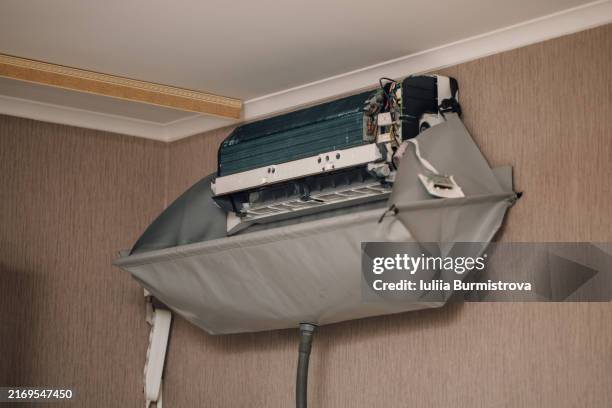 disassembled and dust-free air conditioner hanging from ceiling in corner of domestic room, purifying air from bacteria and providing fresh breathing. - respiratory protection construction stock pictures, royalty-free photos & images