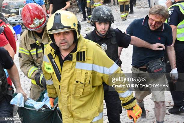 Injured local resident Jaroslav Bazylevych follows Ukrainian rescuers carrying the body of his daughter, who was killed along with her two sisters...