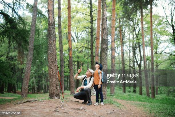 little boy with his grandfather exploring nature in a forest - children bird watching stock pictures, royalty-free photos & images