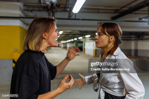 young couple shouting at each other in parking lot on underground floor - aggression stock pictures, royalty-free photos & images