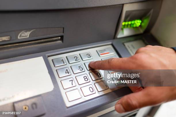 male hand inserting pin code into the atm machine - atm stock pictures, royalty-free photos & images