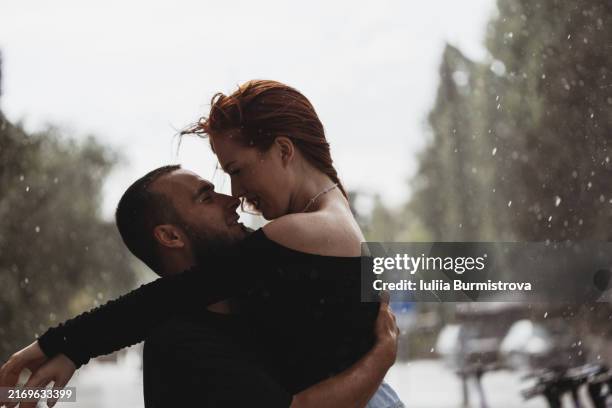 passionate young couple stand on deserted street in warm summer rain waiting for magical first kiss - verführung stock-fotos und bilder