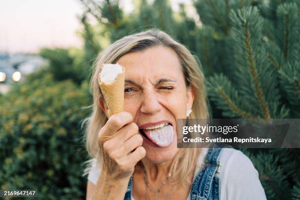 elderly woman enjoying eating ice cream in the city on a summer day - lamber imagens e fotografias de stock