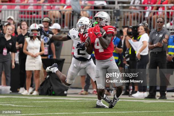 Wide receiver Jeremiah Smith of the Ohio State Buckeyes catches a pass while being guarded by safety Daymon David of the Akron Zips during the third...