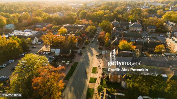 sunset shines above a small neighborhood by the merchants square in colonial williamsburg, virginia. aerial view - virginia road stock pictures, royalty-free photos & images