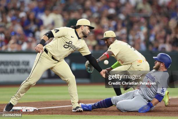 Max Muncy of the Los Angeles Dodgers safely slides into third base ahead of infielder Eugenio Suárez of the Arizona Diamondbacks during the second...