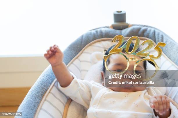 funny portrait of cute dancing baby celebrating with new year 2025 glasses. happy new year 2025 greeting. funny real photo postcard. copy space