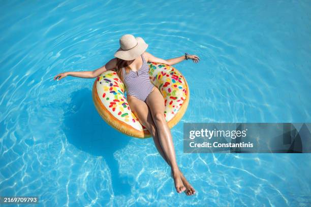beautiful girl enjoying in the pool on an inflatable donut - tubing stock pictures, royalty-free photos & images