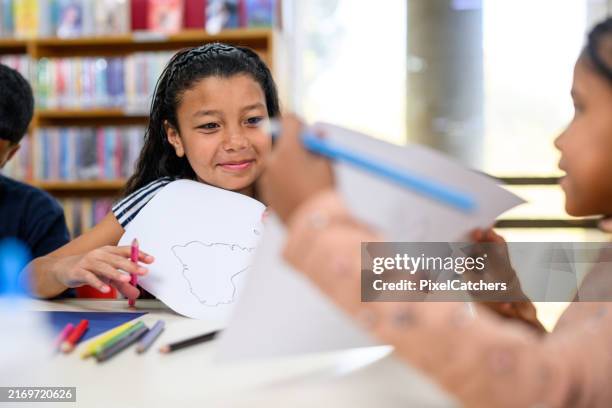 little girls colouring continents and showing each other - cartography stock pictures, royalty-free photos & images