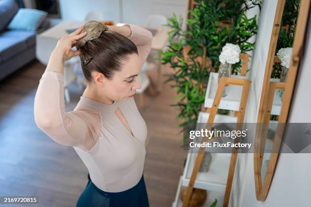 before the dance begins, the ballerina perfects her hair in front of the mirror. - atado-no-topo-da-cabeça imagens e fotografias de stock