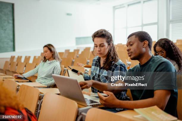multiethnische gruppe von weiblichen und männlichen studenten, die laptop benutzen, während sie im college-raum sitzen - ausbildungsschritt stock-fotos und bilder