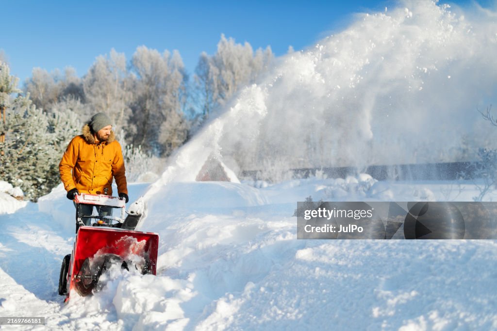 Mid adult man using snowblower