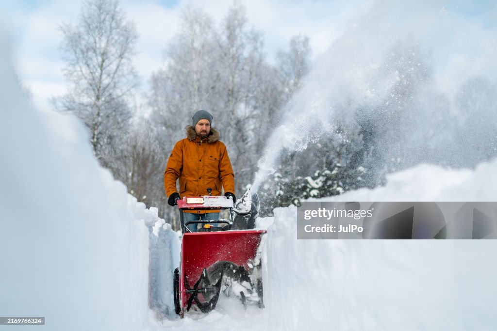 Mid adult man using snowblower