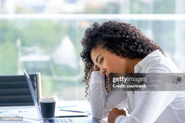 upset woman working on a laptop computer in the office. she looks worried, frustrated and depressed. - slow stock pictures, royalty-free photos & images