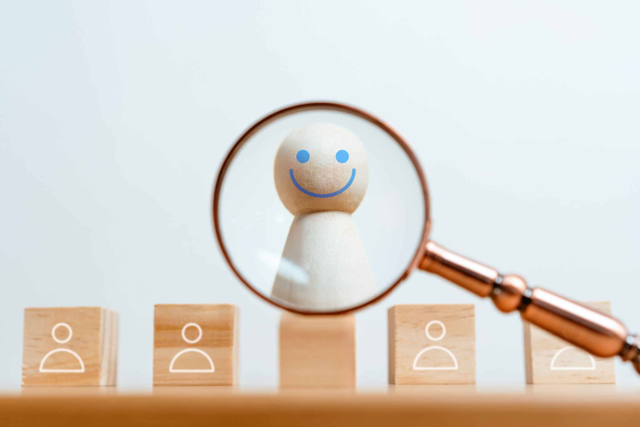 A wooden figurine is looking at a person through a magnifying glass A wooden figurine is looking at a person through a magnifying glass