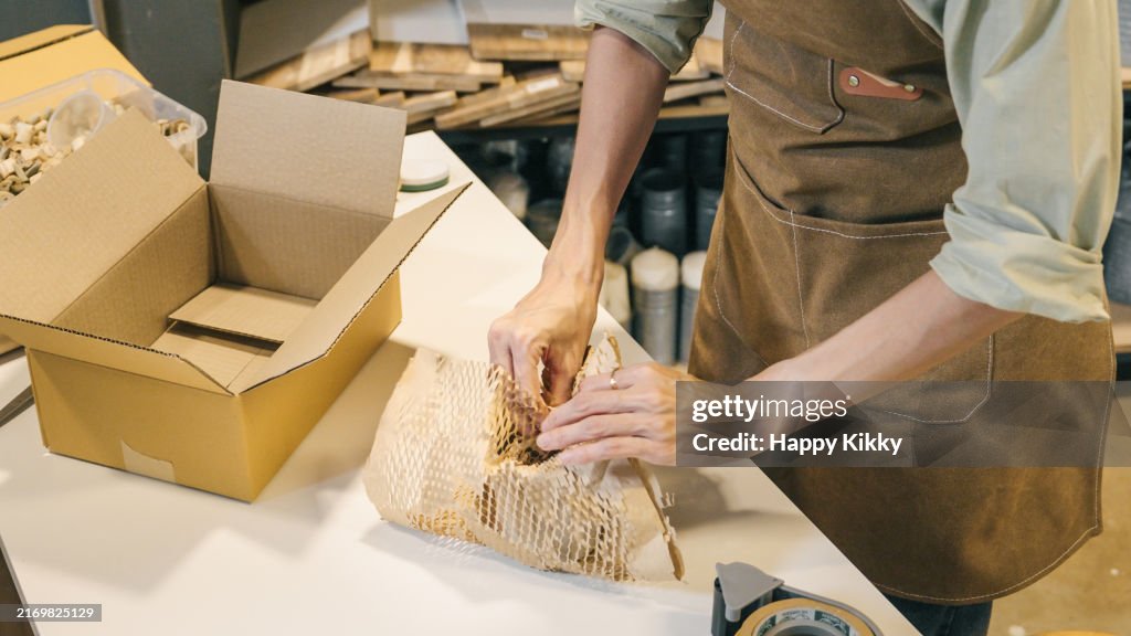 A small business warehouse worker owner packing eco friendly brown paper honeycomb wrapped with environmental Sustainability friendly paper biodegradable materials before shipping to customers,zero waster and plastic free