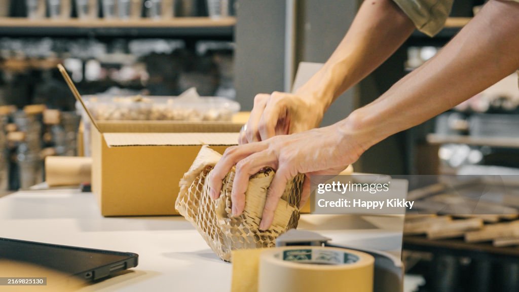 A small business warehouse worker owner packing eco friendly brown paper honeycomb wrapped with environmental Sustainability friendly paper biodegradable materials before shipping to customers,zero waster and plastic free
