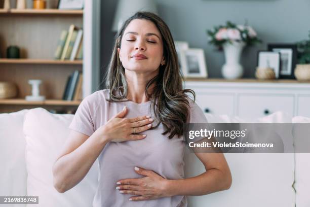 woman doing calming breathing exercises at home. - inademen stockfoto's en -beelden